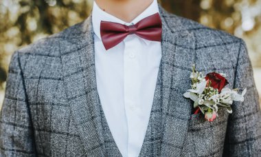 Takım elbiseli damat çiçek yaka çiçekli ve kırmızı papyonlu.