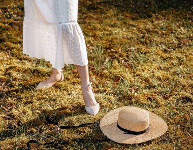 Bahçedeki çimlerin üzerinde hasır şapkalı bir kız. Yazın veya ilkbaharda piknik.