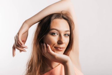 Gülümseyen ve poz veren güzel bir genç kız beyaz izole bir arka planda kameraya bakıyor. Pozitif esmer kadın. Nazik bak. Güzel surat..