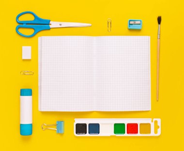 Modern beyaz, mavi, sarı ofis masaüstü, okul gereçleri ve kırtasiye malzemeleriyle dolu. Masanın etrafında mesaj için boş alan var. Okula dönüş konsepti dairesi modelle yatıyordu.