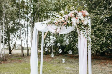 Doğada bir düğün töreni için kemeri çiçekler ve kumaşla süslemek.