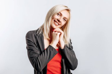 Güzel, mutlu, genç bir kız gri arka planda gülümsüyor.