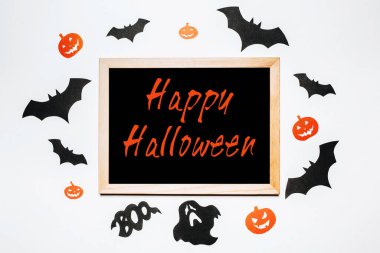 Cadılar bayramı konseptin kutlu olsun. Yarasalar, balkabakları ve hayaletlerle dolu beyaz ve siyah arkaplan üzerine Mutlu Cadılar Bayramı metni içeren not defteri