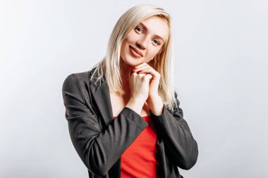 Güzel, mutlu, genç bir kız gri arka planda gülümsüyor.