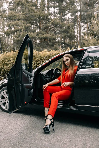 Una Hermosa Joven Con Mono Rojo Sienta Volante Coche Negro — Foto de Stock