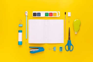 Modern beyaz, mavi, sarı ofis masaüstü, okul gereçleri ve kırtasiye malzemeleriyle dolu. Masanın etrafında mesaj için boş alan var. Okula dönüş konsepti dairesi modelle yatıyordu.