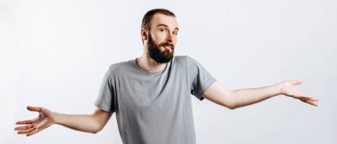 Kameraya bakarken gülümseyen neşeli bir gencin portresi, beyaz bir arka planda cehalet yüzünden ellerini kaldırıyor ve reklam için bir yer arıyor.