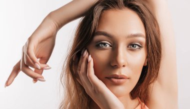 Gülümseyen ve poz veren güzel bir genç kız beyaz izole bir arka planda kameraya bakıyor. Pozitif esmer kadın. Nazik bak. Güzel surat..