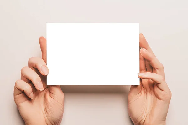 Γυναικεία Χέρια Κρατούν Ένα Λευκό Φύλλο Χαρτιού Μπεζ Φόντο Διαφημιστικός — Φωτογραφία Αρχείου