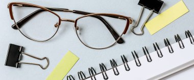 Kırtasiyeli işyerinin düz düzeni. Beyaz ve mavi arkaplana izole edilmiş metin, kalem, gözlük, defter, klasör ve raptiye dolu boş çıkartmalar. Ofis malzemeleri hazır..