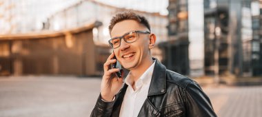 Büyük bir şehrin caddesinde gözlüklü, akıllı telefonlu yakışıklı bir adam. İş adamı şehir planıyla ilgili telefonda konuşuyor.