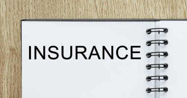 Tahta masaüstünde INSURANCE metni olan not defteri. İş ve finans kavramı