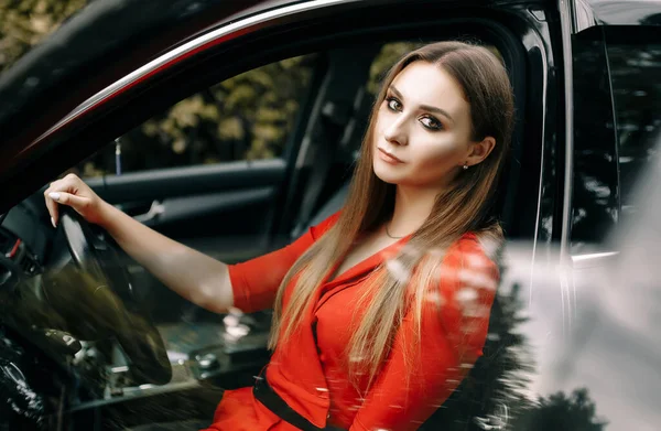 Krásná Mladá Dívka Červené Kombinéze Sedí Volantem Černého Auta Prázdné — Stock fotografie