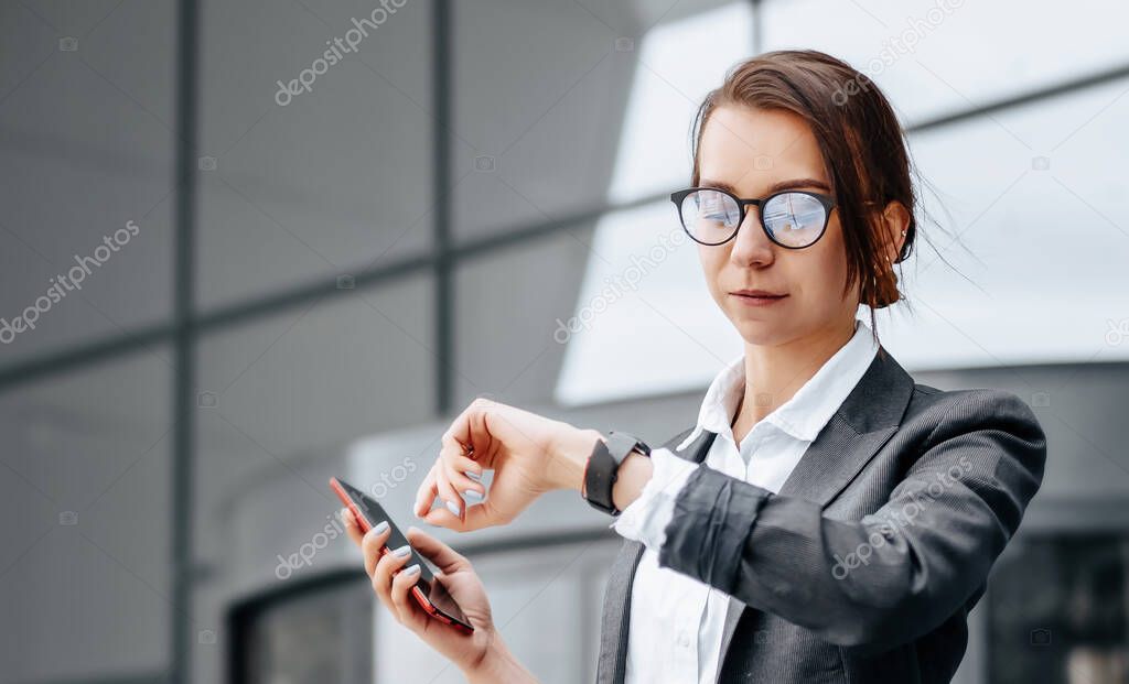 A business woman checks the time in the city during a working day waiting for a meeting. Discipline and timing. An employee goes towards a corporate meeting.