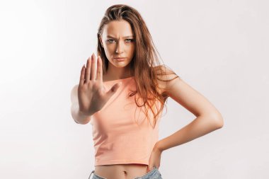 Kes şunu! Yeter dedim. Genç ve güzel kız efekti durdurmak için elini kameraya uzatıyor. Gri arka planda, turuncu giysili bir kadın. Kötü olaylar, umutsuzluk ve tehdit