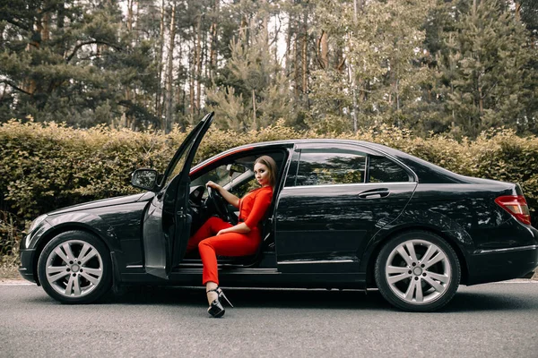 Una Hermosa Joven Con Mono Rojo Sienta Volante Coche Negro — Foto de Stock