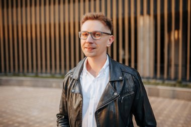 Büyük bir şehrin caddesinde gözlüklü, akıllı telefonlu yakışıklı bir adam. İş adamı şehir planıyla ilgili telefonda konuşuyor.