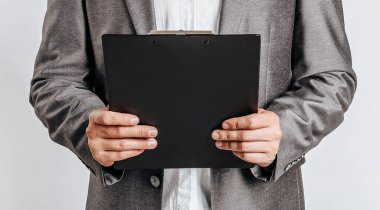 Gözlüklü, takım elbiseli, iş evrakları ve beyaz arkaplan çizelgeleri olan yakışıklı bir genç.