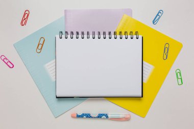 Not defteri, egzersiz kitabı ve kalem masaya. Fotokopi odasında beyaz arka planda. Okula geri dön.