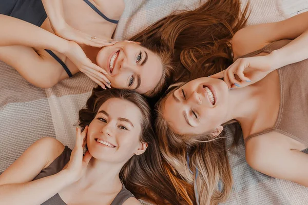 女人休息 玩得开心 女朋友们在家里躺在地板上 躺在枕头上笑 树女们做了自制的脸和头发美容面具 女人照顾年轻的皮肤 — 图库照片