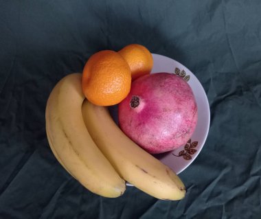 Eski bir tabakta mandalina, nar ve muz..