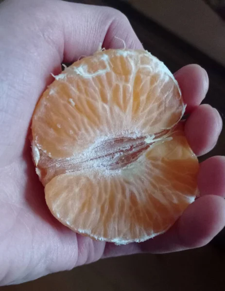 Kadının elinde soyulmuş mandalina.