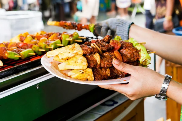 Barbecue grill, geplaatst op een witte plaat in de hand. — Stockfoto