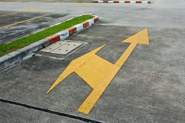 A yellow traffic arrow signage on an asphalt road indicating a d — Stock Photo, Image