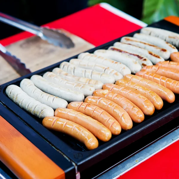 Saucisses fraîches et hot-dogs grillés en plein air sur un barbecue à gaz g Photos De Stock Libres De Droits