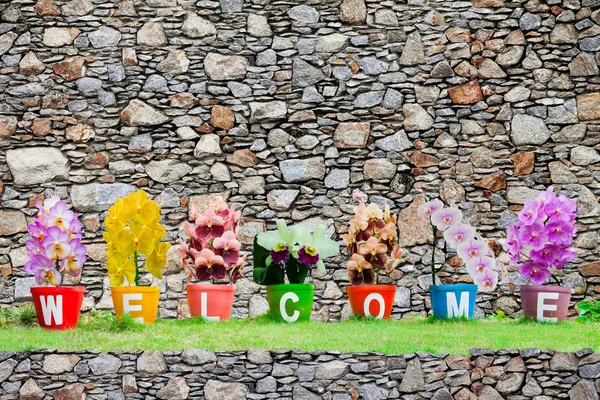 Palabra de bienvenida hecha de flores de orquídea Jardiniere aisladas en st — Foto de Stock