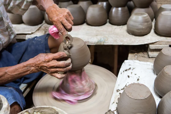 dirty hands making pottery in clay on wheel