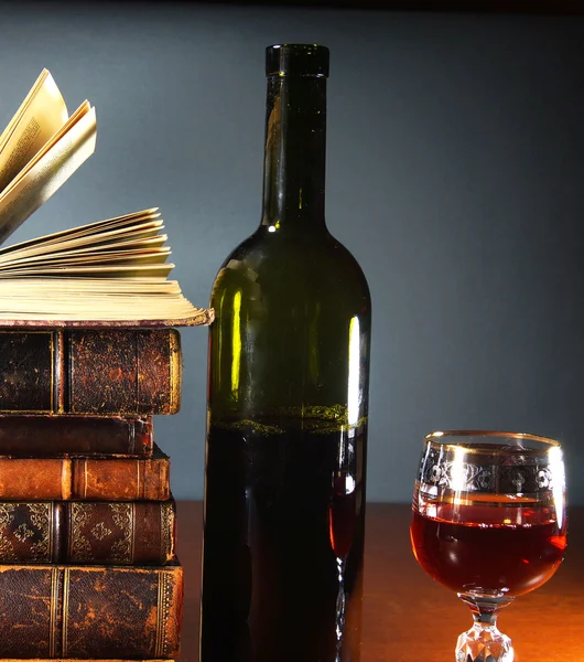 Libros antiguos, una copa de vino tinto y una botella —  Fotos de Stock