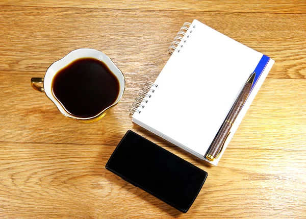 Taza de café, un teléfono y un bloc de notas — Foto de Stock