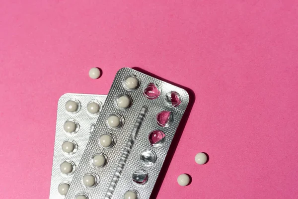 Birth control pills on pink, minimal flat lay