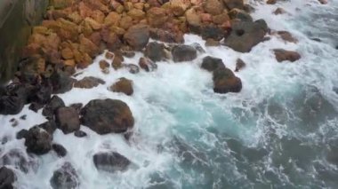 Karadeniz 'in mavi dalgaları, kahverengi kayaları dövüyor. Deniz köpüğü manzaralı. Taş