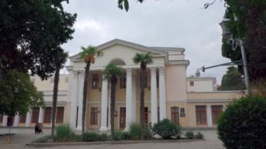 Yunan tarzında sütun binası. Palmiye ağacında oturan kuş