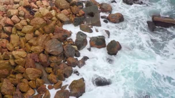 Голубые волны черного моря, бьющиеся коричневыми камнями. Вид сверху на море с пеной. Камни — стоковое видео