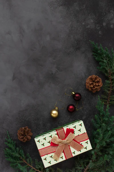 Fond de Noël avec boîte cadeau et décorations de branches d'arbre et de cônes. modèle de carte de vœux. fond sombre, espace de copie. — Photo