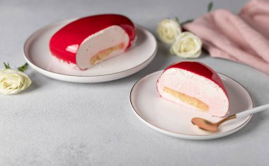 Gri arka planda beyaz tabakta beyaz güllerle bir dilim kremalı pasta.