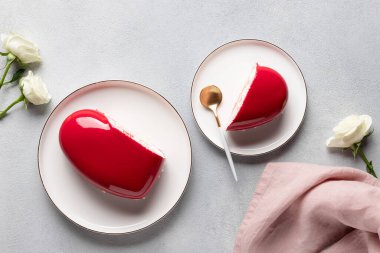 Gri arkaplanda kırmızı kalp kremalı pasta ve beyaz güller..