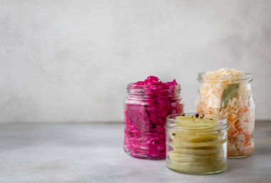 Kavanozlarda çeşitli mayalanmış sebzeler. Lahana, yeşil domates. gri arkaplan, kopyalama alanı, yatay resim