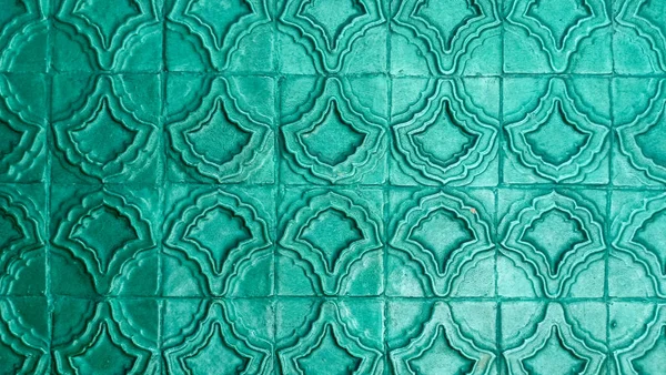 Parlak yeşil-mavi tekrarlayan geometrik desenli yatay arkaplan dokusu.