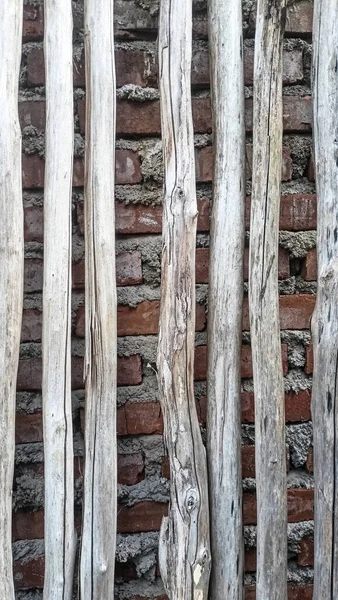 Açık gri ahşap veya bambudan oluşan bir sıranın dikey dokusu ve arka plan olarak kırmızı tuğla bir duvar..