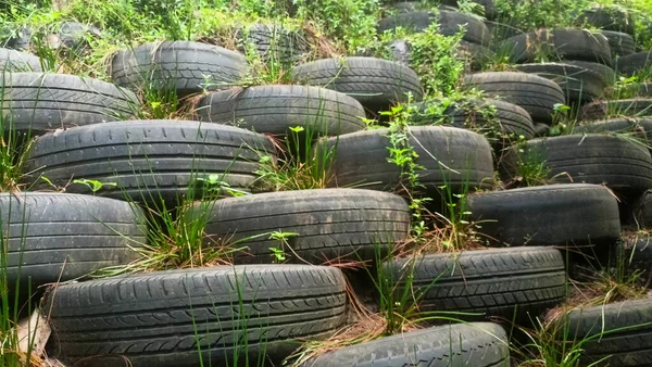 Yamaçta istinat duvarı ya da bariyer olarak yerleştirilmiş kullanılmış lastik yığınının görüntüsü.