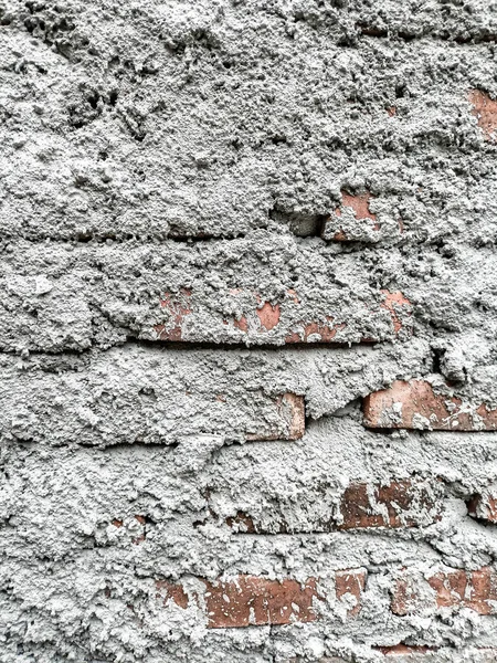 Sert, kalın ve düz olmayan beton veya alçı yüzey dokusu, tuğla bir duvarı örterek.