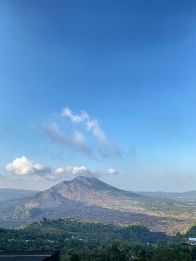 Açık mavi gökyüzü ile geniş bir dağ manzarası, yüksek irtifada huzurlu bir atmosfer..
