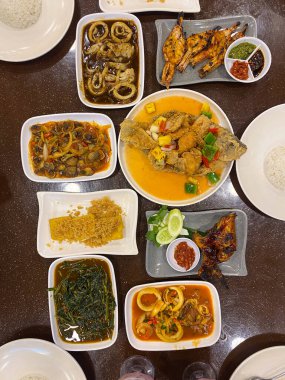 Masada servis edilen çeşitli Hint yemekleri beyaz tabaklar ve kırmızı masa örtüsü, iştah açıcı bir gösteri..