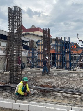 Jakarta, Endonezya - 27 Kasım 2025: İnşaat işçisi güçlendirilmiş beton kazığın yanında yeşil üniformalı.
