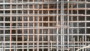 Çelik takviye çubuklarının (inşaat çubuğu) ağ düzeninin zemin veya duvar yapısı için dökmeye hazır bir ızgara demetinde yakın görüntüsü.