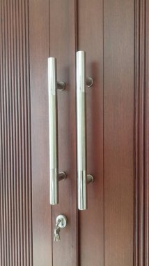 Kahverengi ahşap kapı. Uzun, dikey gümüş saplı..